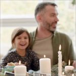 A man and a child smiling at the table with candles