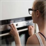 A woman adjusting the settings on an oven