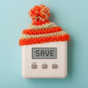 Thermostat with a knitted hat on top showing the word 'Save' on its screen