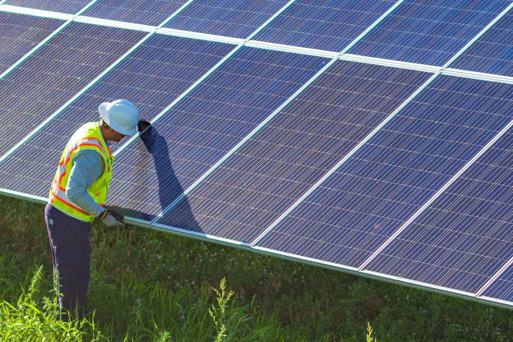 A man with a hard hat working on a solar panel