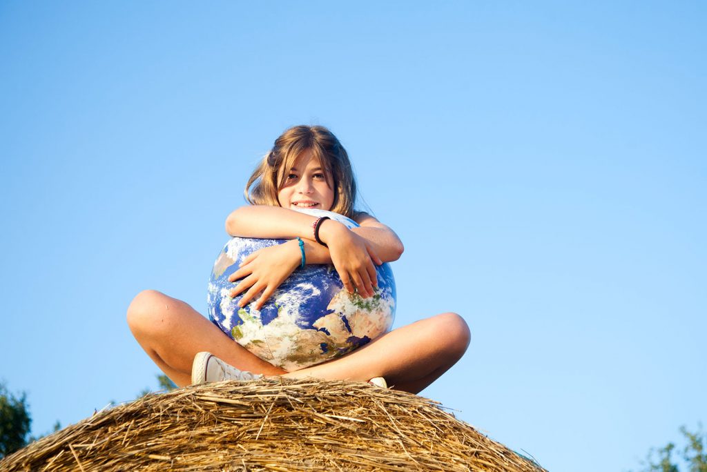 A young girl holding a ball depicting the Earth