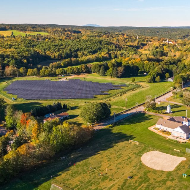 A community solar garden next to houses and trees
