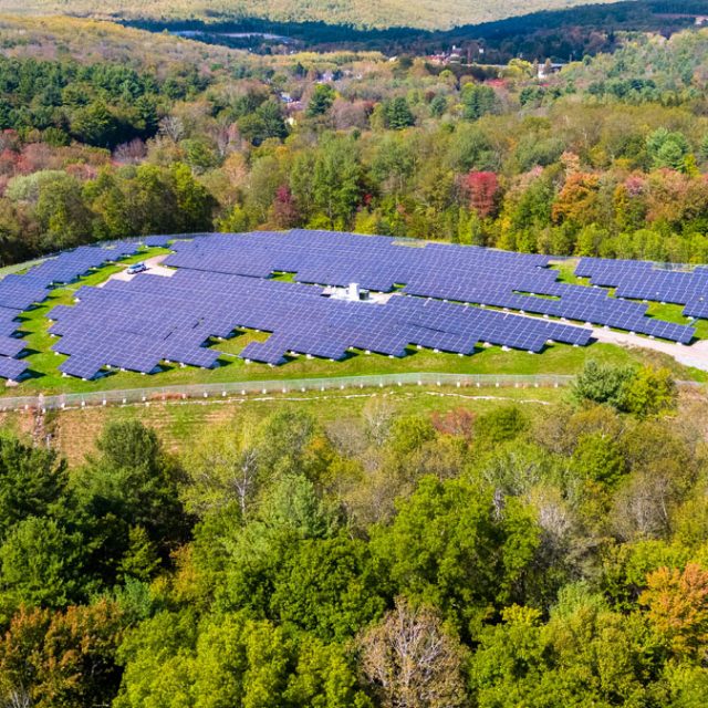 A community solar garden in Massachusetts surrounded by trees