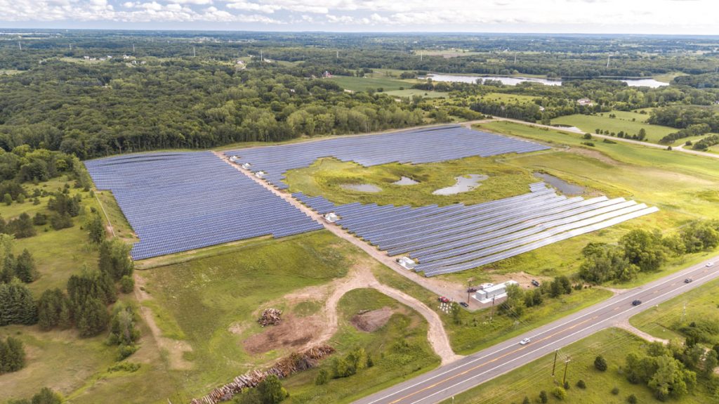 A bird's eye view of a community solar farm with bodies of water in the middle