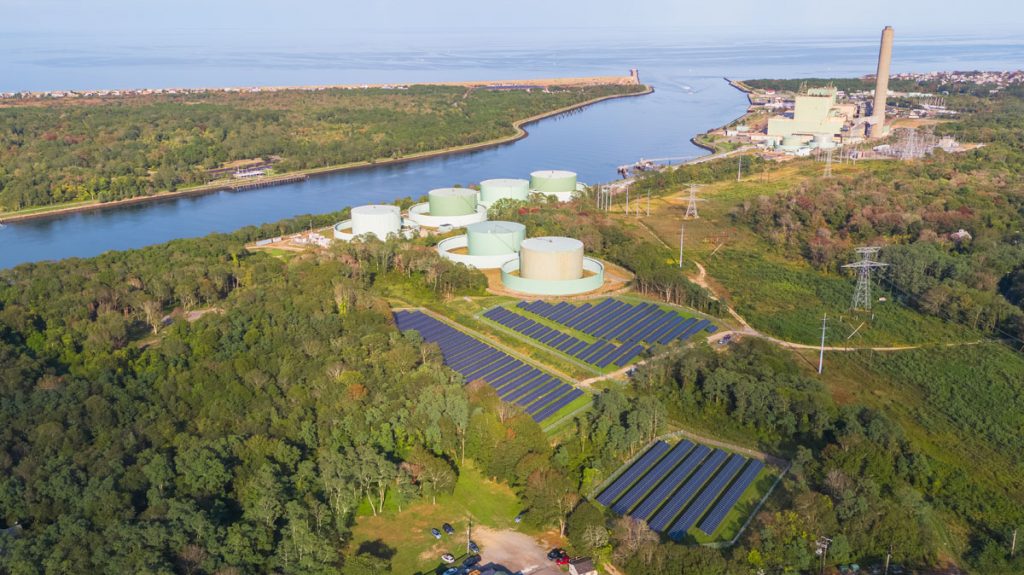 Community solar gardens next to water and industrial plants