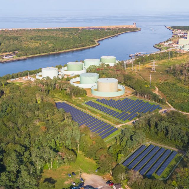 Community solar gardens next to water and industrial plants