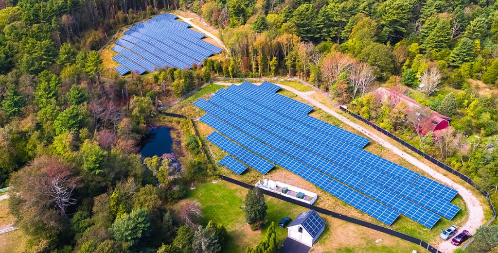A bird's eye view of a community solar farm with blue solar panels