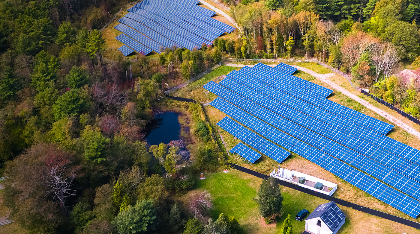 A bird's eye view of a community solar farm with blue solar panels