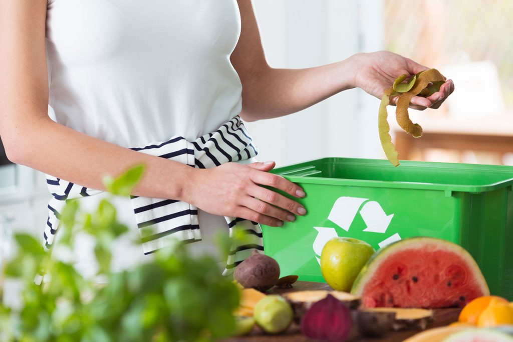 A person placing food scraps in a recycling container