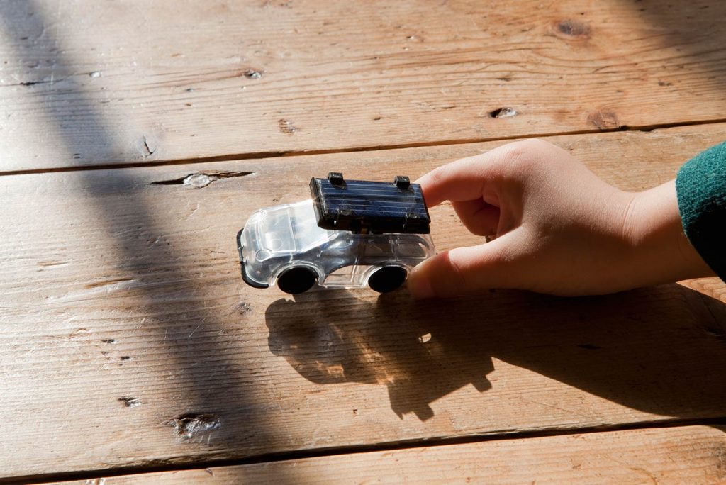 small hand pushing a toy solar car