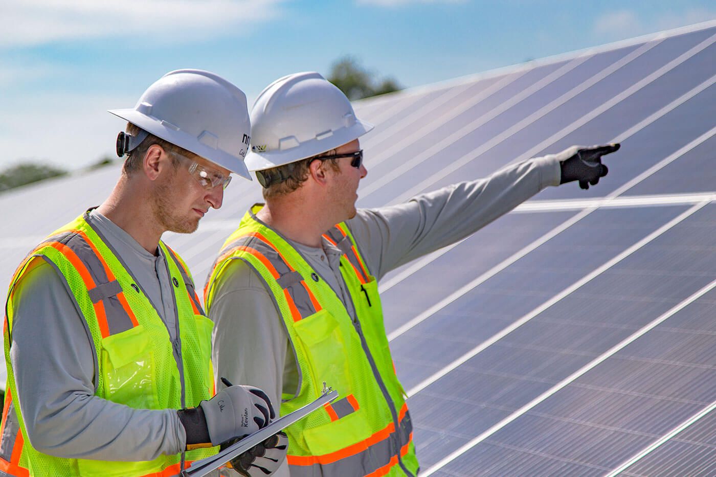 Two men in hard hats checking the solar panels