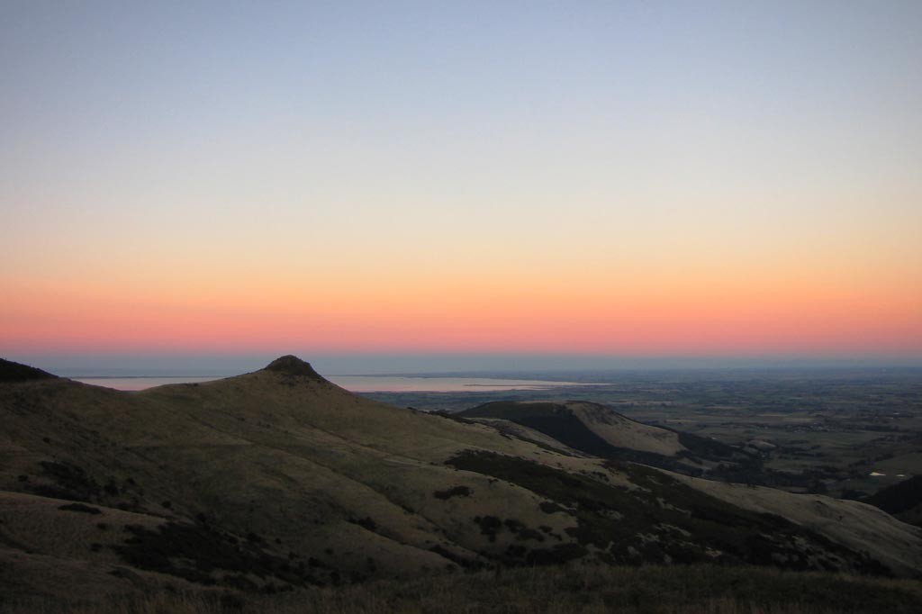 A Belt of Venus in the sky featuring shades of pink, purple, yellow, and blue over the horizon.