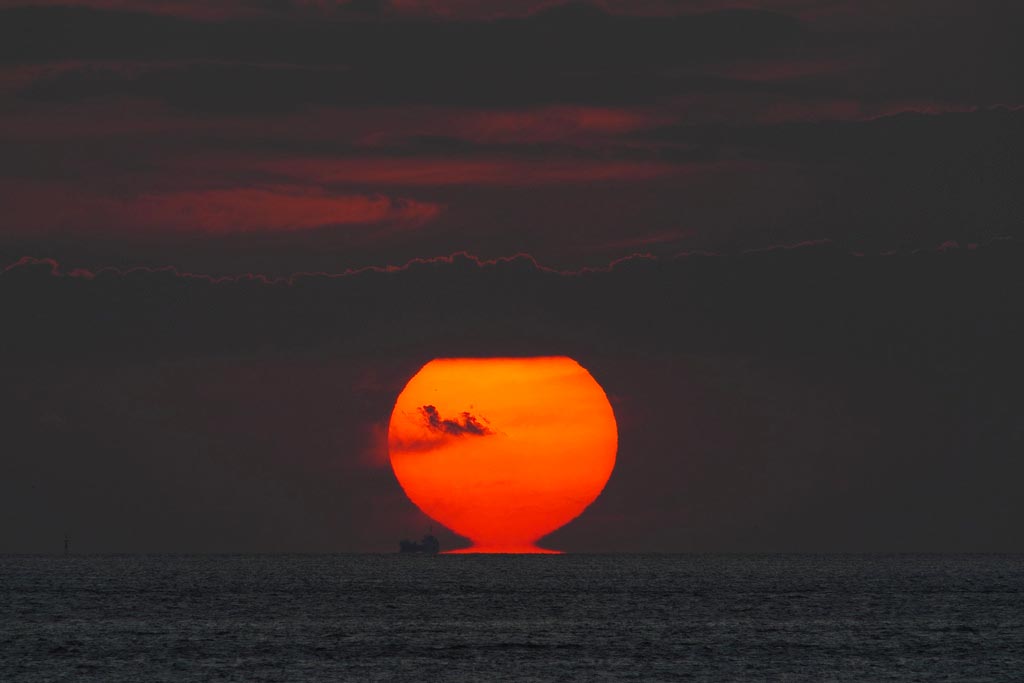 An Omega Sun creating a mirage effect as it appears to be touching the horizon.
