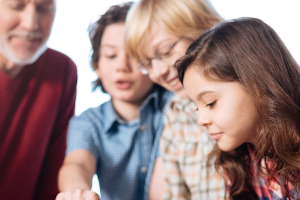 three young children and an older man looking at a tablet