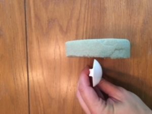 measuring white plastic spoon against foam circle