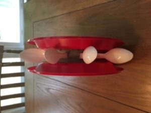 side view of two red plastic plates sandwiching the foam circle with spoons