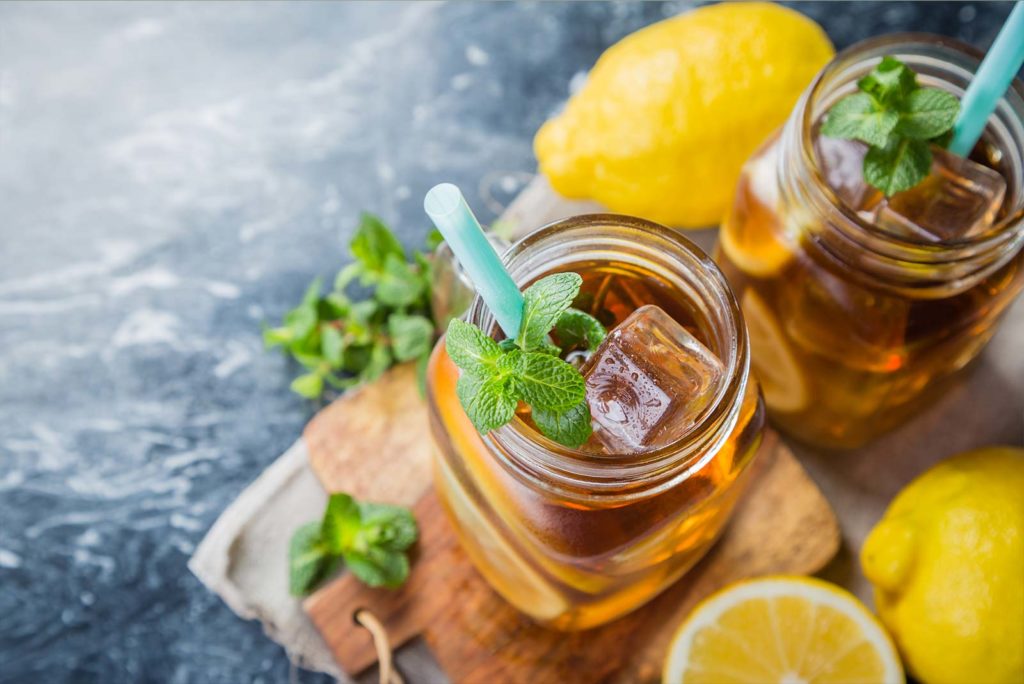 Glass containers filled with tea on a platter with lemons