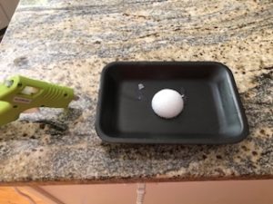 a black tray with half a styrofoam ball glued to it