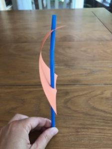 side view of blue plastic straw through hole punches in paper triangle