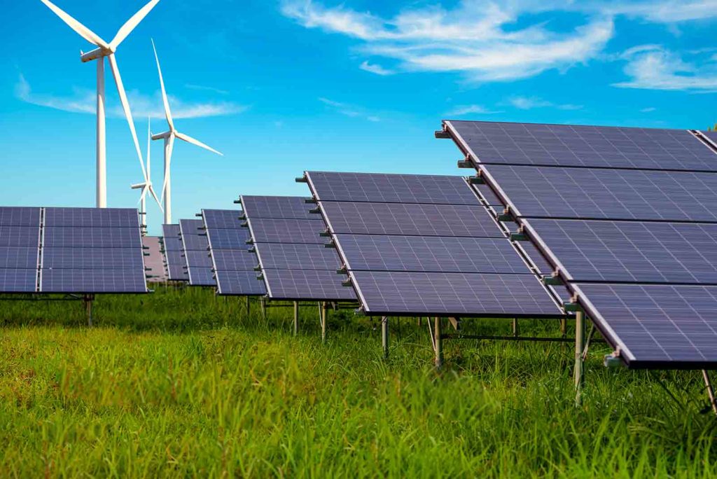 rows of solar panels with wind turbines behind