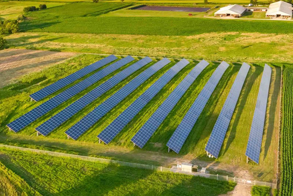Aerial view of rows of solar panels in a solar farm field