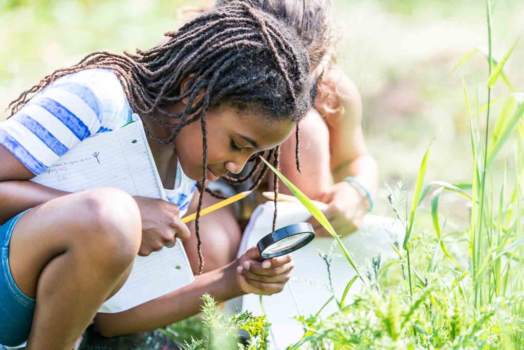 young girl looking with a magnifying class