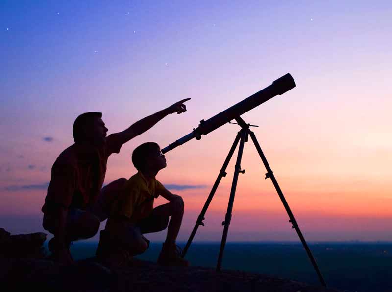 Man and boy looking through telescope