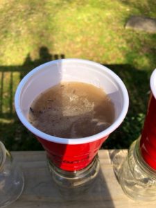 top view of sandy water in red cup labeled "sand" in glass jar