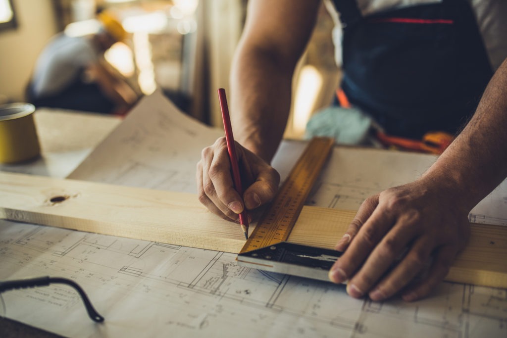 Carpenter drawing line on piece of wood