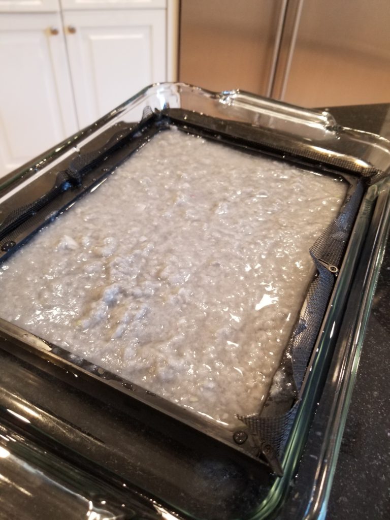 paper pulp in water on mesh screen in baking dish