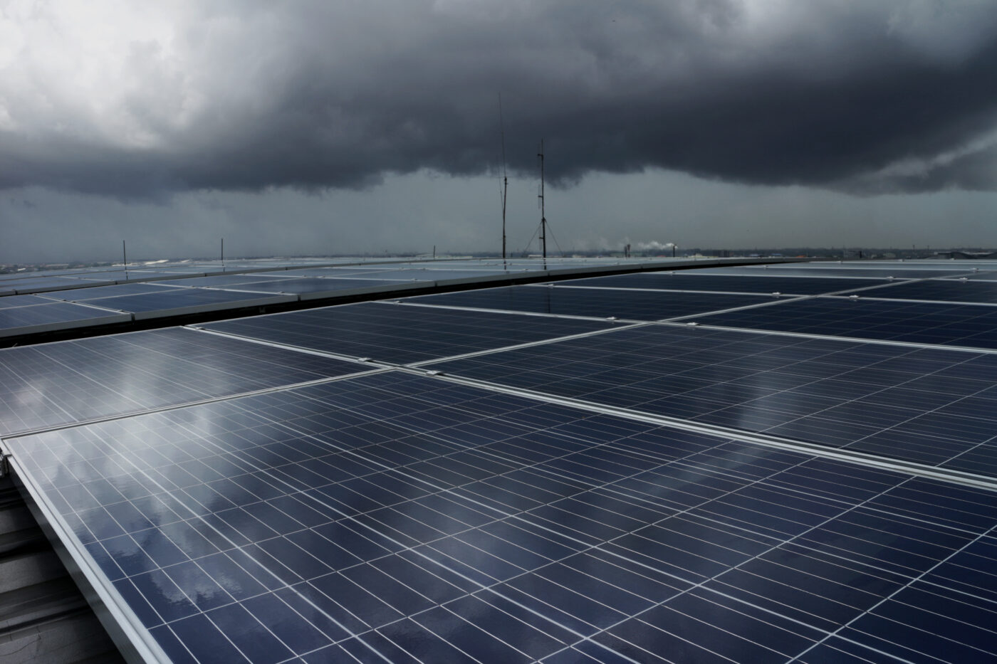 Solar panels under dark grey, cloudy sky