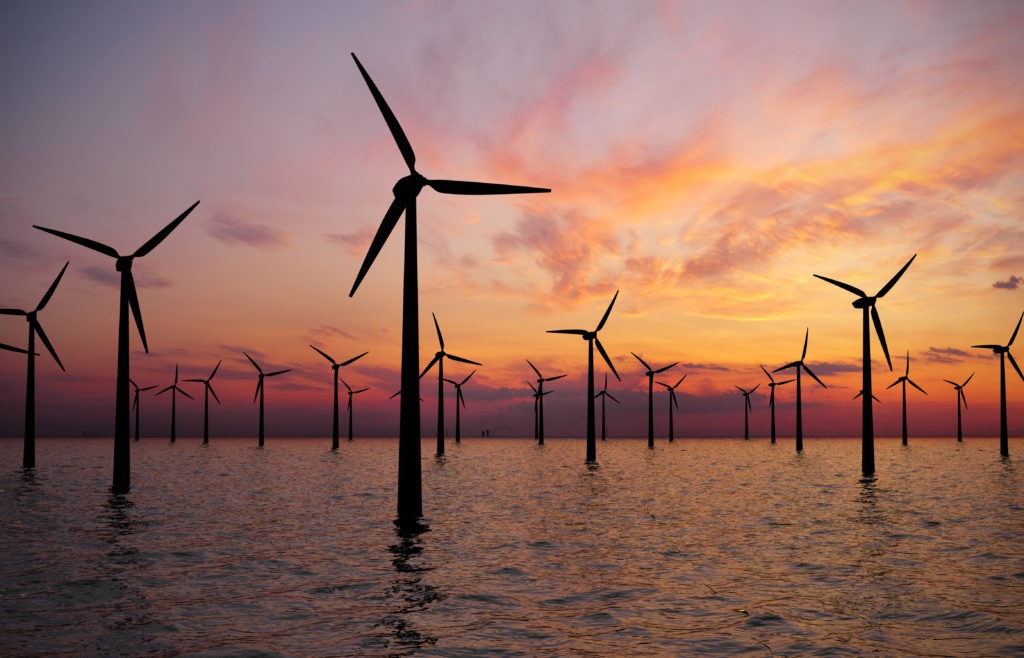 wind turbines in water against sunset