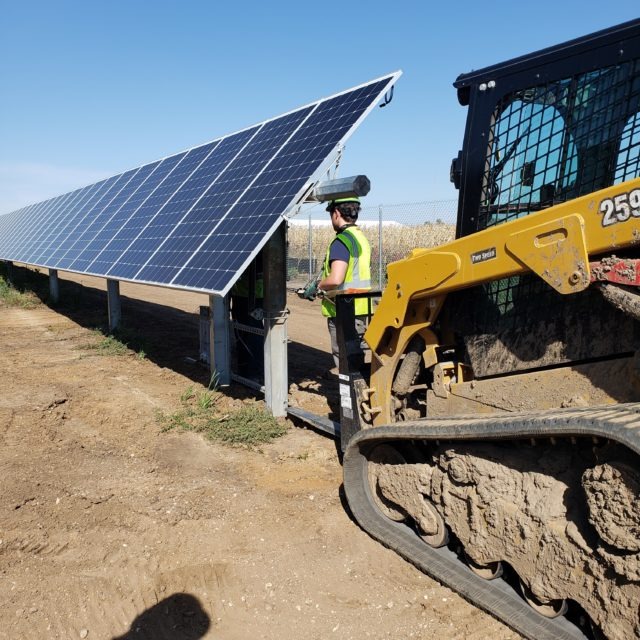 heavy equipment and workers installing solar panels