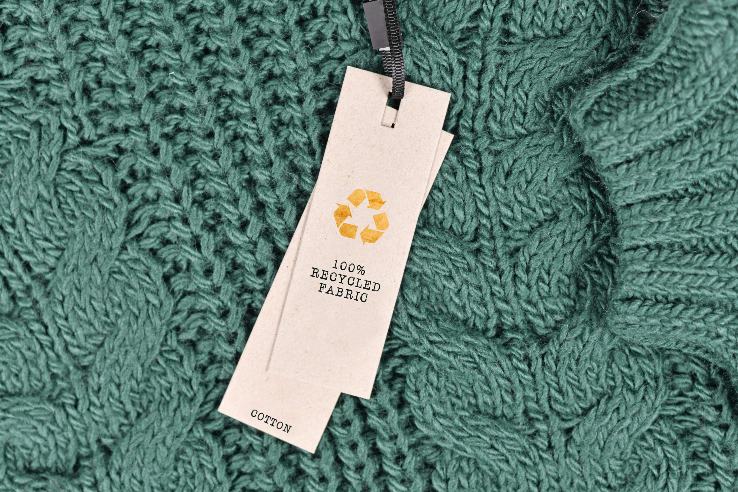 A green cotton cable-knit sweater with a “100% recycled fabric” tag